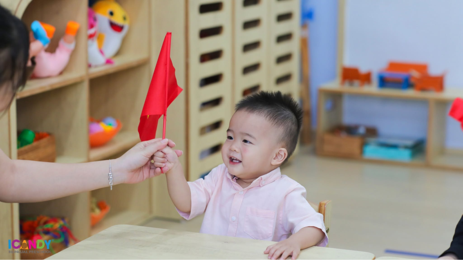 Ánh mắt hân hoan và nụ cười rạng rỡ của em bé ICANDY Preschool khi được cô giáo trao tận tay lá cờ đỏ sao vàng nhân dịp mừng Quốc Khánh 2/9