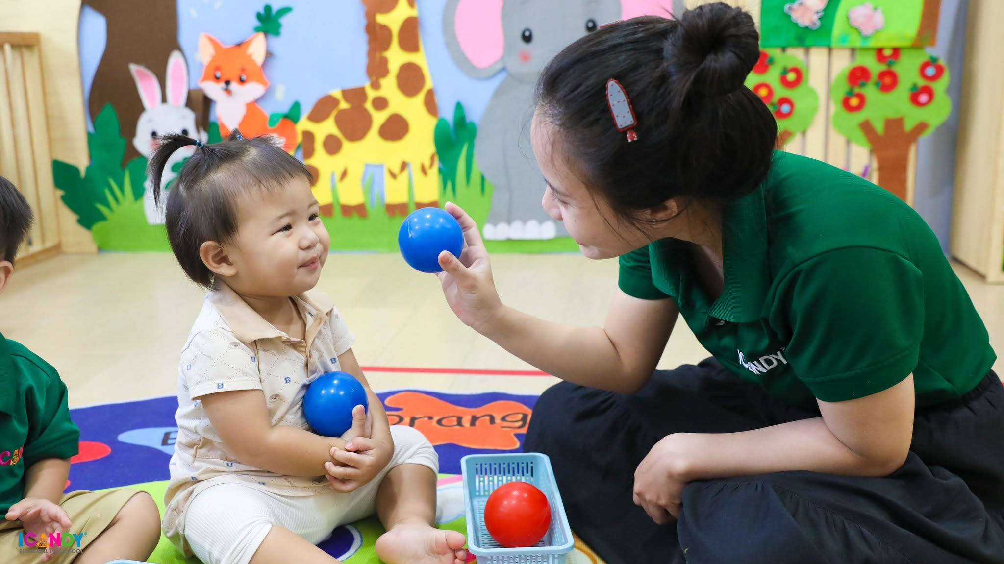 C&ocirc; gi&aacute;o &acirc;n cần tương t&aacute;c v&agrave; hướng dẫn b&eacute; ph&acirc;n biệt m&agrave;u sắc qua tr&ograve; chơi b&oacute;ng nhựa