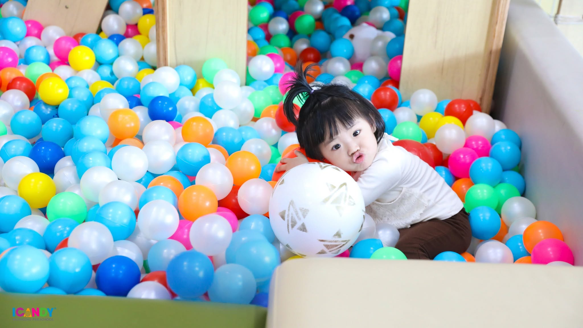 B&eacute; g&aacute;i đ&aacute;ng y&ecirc;u vui chơi v&agrave; tạo d&aacute;ng tinh nghịch trong nh&agrave; b&oacute;ng sắc m&agrave;u