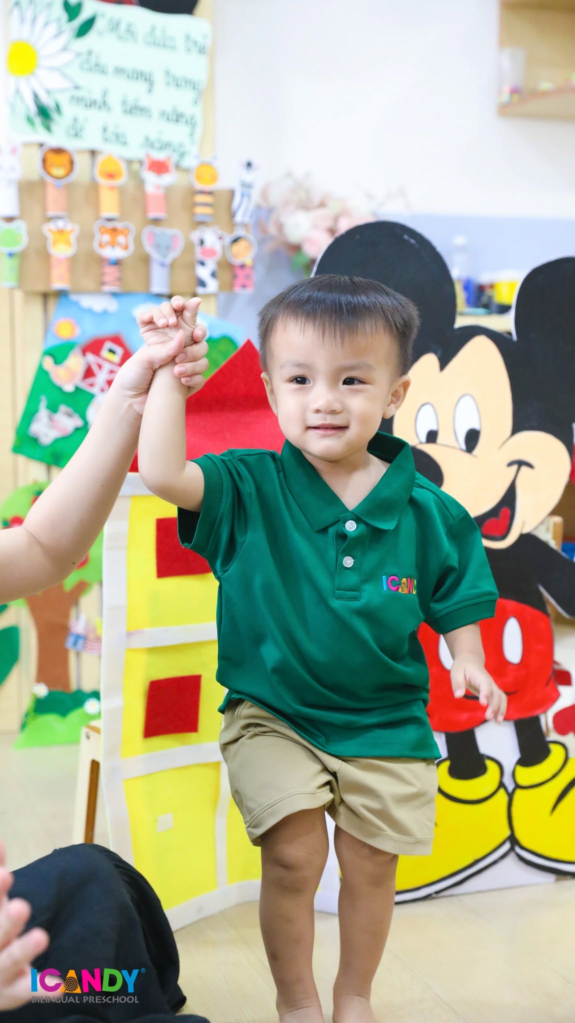 B&eacute; trai tự tin, dạn dĩ nắm tay c&ocirc; gi&aacute;o c&ugrave;ng tham gia hoạt động vận động tại lớp