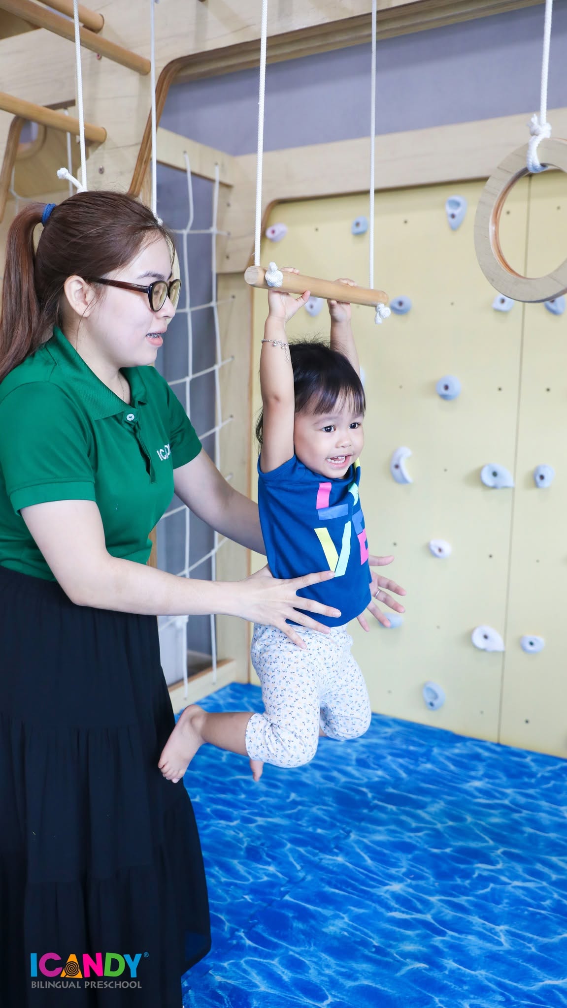 C&ocirc; gi&aacute;o &acirc;n cần n&acirc;ng đỡ b&eacute; g&aacute;i tập x&agrave; đu trong giờ r&egrave;n luyện vận động thể chất