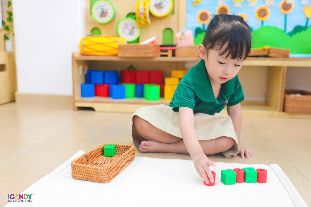 Bé mầm non ICANDY Preschool tập trung thả bóng gỗ rèn luyện kỹ năng vận động tinh