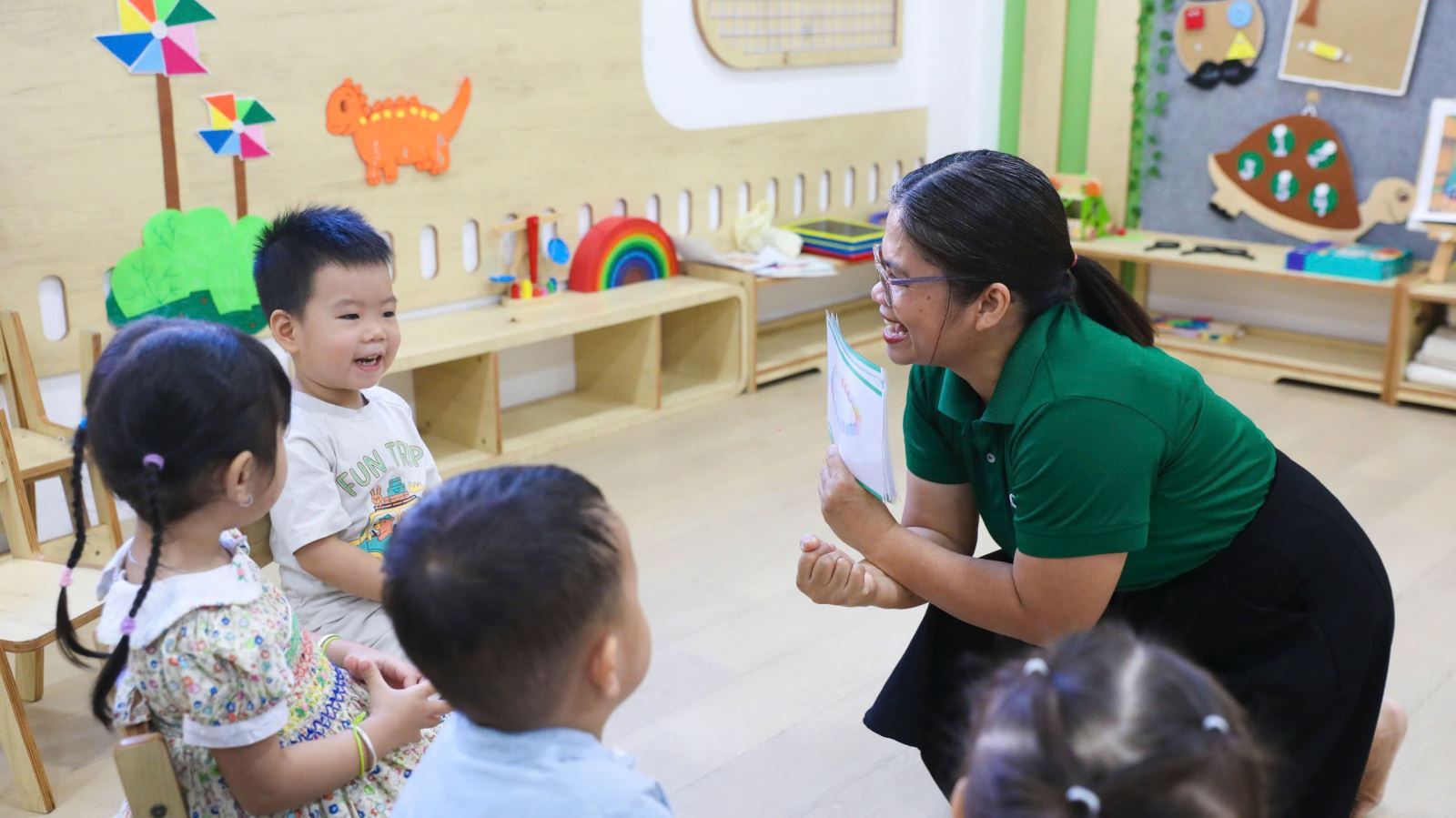 Cô giáo mầm non vui vẻ kể chuyện và tương tác cùng các bé trong giờ học