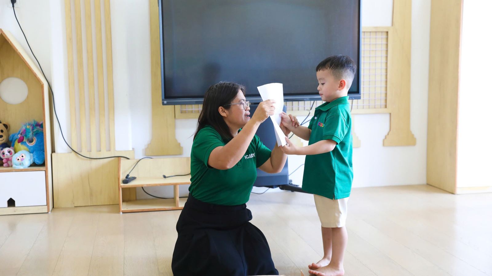 Bé mầm non ngoan ngoãn đưa hai tay tương tác cùng cô giáo trong giờ học tại ICANDY