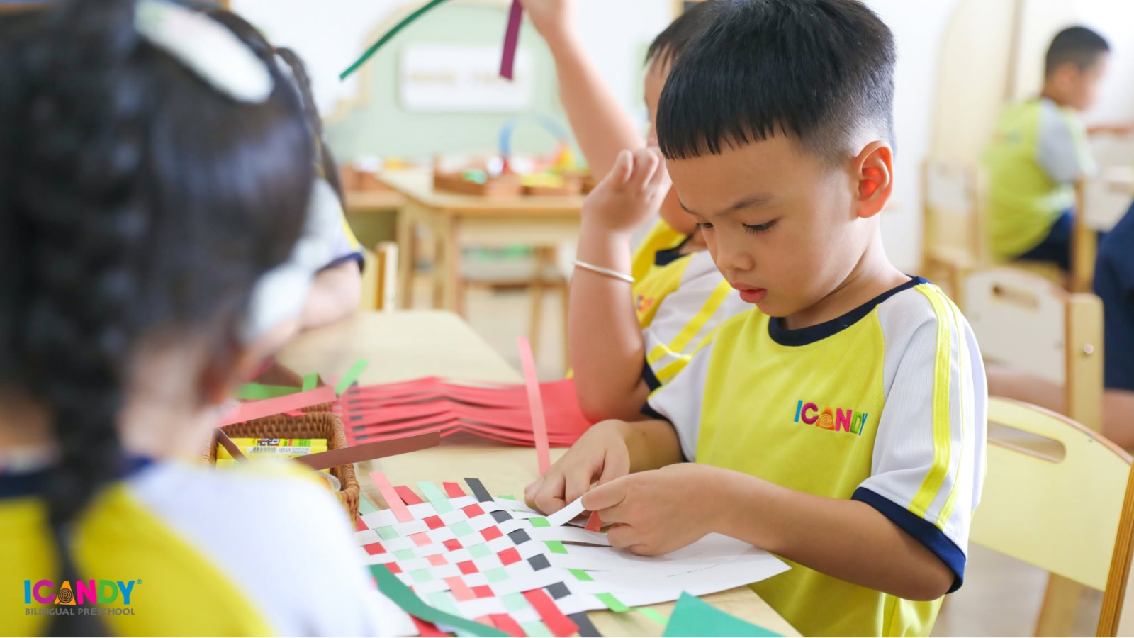 Sự tập trung cao độ và đôi tay khéo léo của em bé ICANDY Preschool khi tỉ mỉ thực hiện hoạt động đan nan giấy thủ công tại lớp